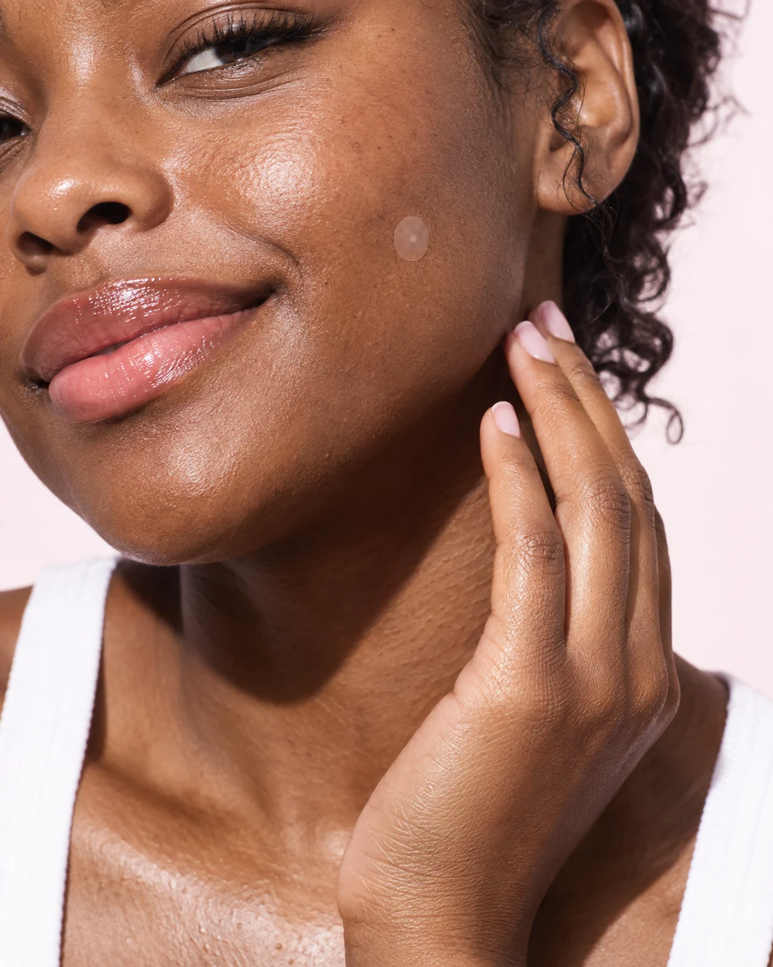 A close-up of a woman wearing a translucent pimple patch on her cheek